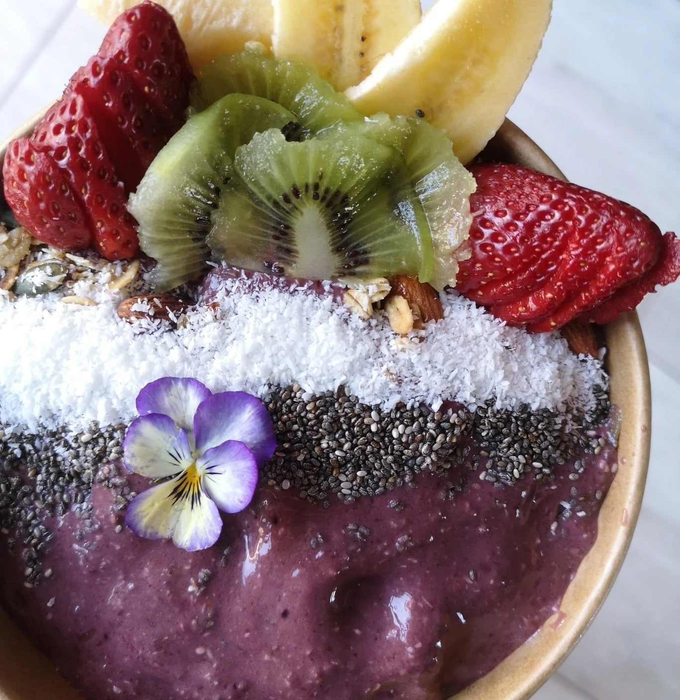 A berry smoothie bowl topped with fruit, coconut and chia