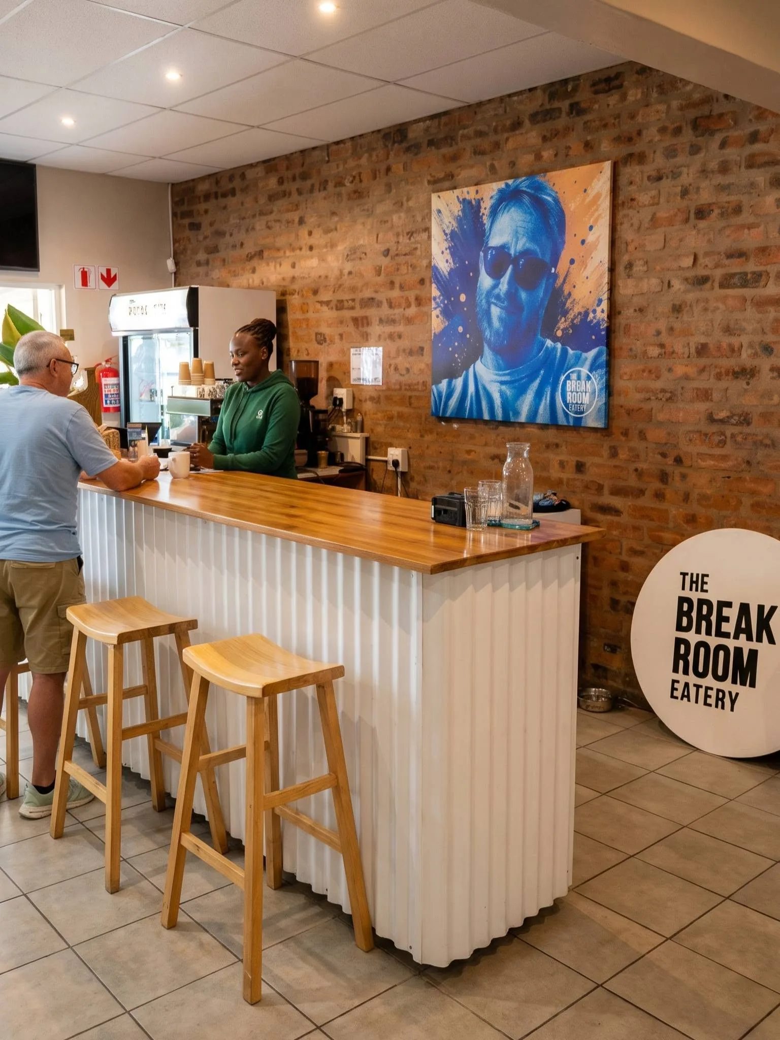 Customers at the counter under the painting of Lee on the brick wall