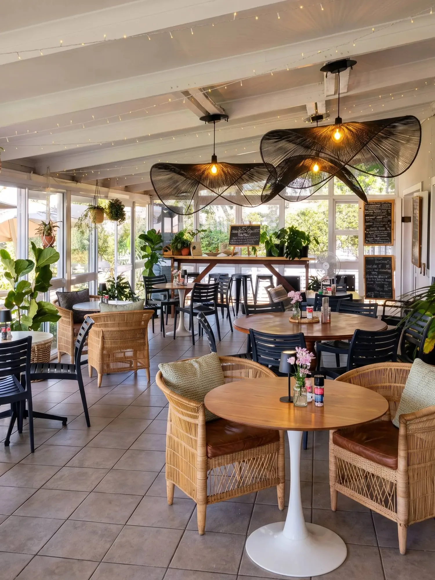 The sunroom with round tables, cane chairs and hanging woven lights