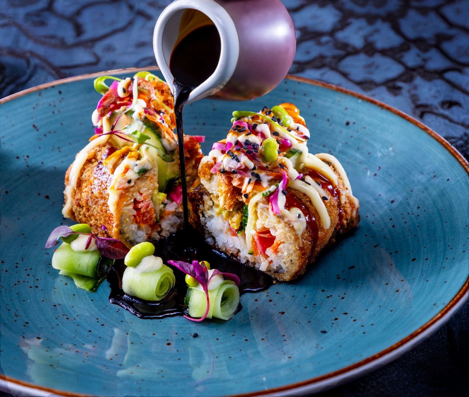 Sauce being poured over the Original SushiDogg on a blue plate