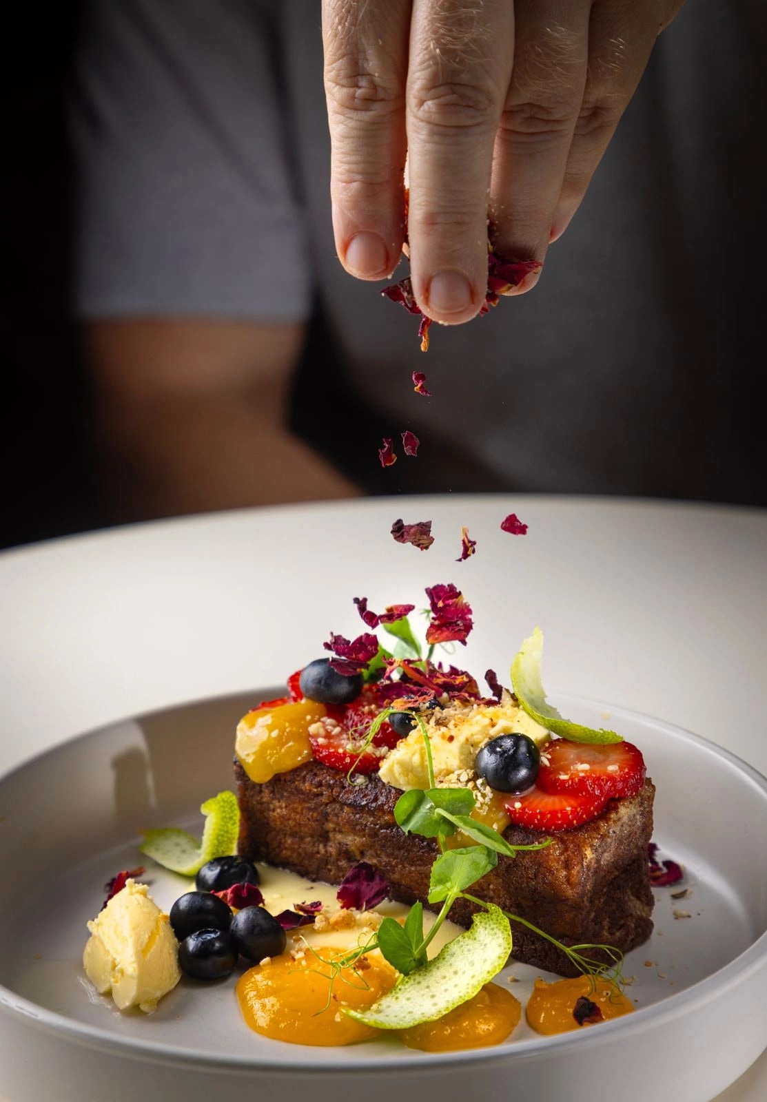 Lee finishing a plated dessert with dried rose petals